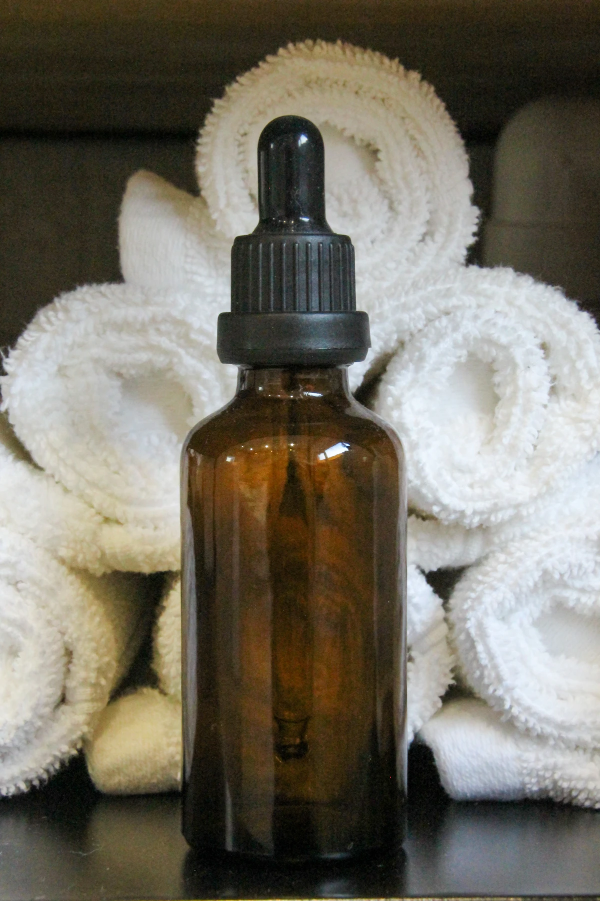 An amber dropper bottle resting on white towels